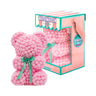 Bear made out of pink-colored faux marshmallows. The bear is adorned with a green ribbon tied into a bow around its neck, and it is packaged in a clear-front gift box with a pink and white striped design. The top of the box features a teal and pink label that reads "MARSHMALLOW BEAR." This delightful creation is an excellent gift idea for various occasions such as anniversaries, birthdays, graduations, Christmas, Valentine's Day, or simply as a unique gift for someone special.
