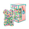 Bear made out of pink, yellow, and green-colored faux marshmallows. The bear is adorned with a green ribbon tied into a bow around its neck, and it is packaged in a clear-front gift box with a pink and white striped design. The top of the box features a teal and pink label that reads "MARSHMALLOW BEAR." This delightful creation is an excellent gift idea for various occasions such as anniversaries, birthdays, graduations, Christmas, Valentine's Day, or simply as a unique gift for someone special.