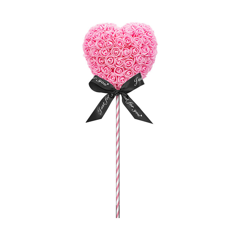 A heart-shaped lollipop with pink flowers, standing on a pink striped stick, and adorned with a black ribbon reading "Just for you." The perfect gift for anniversaries, birthdays, graduations, Christmas, Valentine's, gender reveal and more. A timeless, romantic gift and a beautiful decoration. The durable nature of the materials make it a lasting memento for any special occasion.
