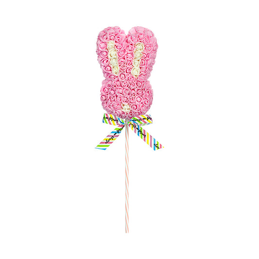 A light pink floral bunny lollipop with a patterned ribbon on a striped stick, featuring a playful arrangement of roses in a bunny shape.