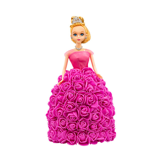 This image features a doll with blonde hair and blue eyes, dressed in a hot pink gown adorned with rose embellishments. The gown has a strapless bodice and a voluminous skirt made entirely of hot pink roses. The doll wears a golden tiara and a matching necklace.