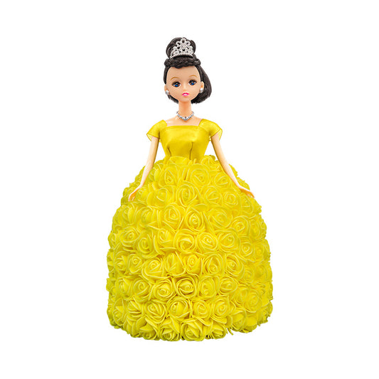 Featured is a doll with black hair and green eyes, donning a vibrant yellow gown with a strapless bodice and a full skirt adorned with yellow roses. The doll is crowned with a silver tiara and complemented by a matching necklace.