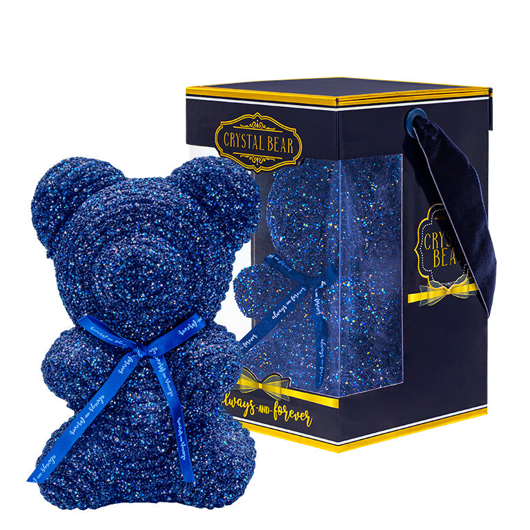 A plastic shaped dark blue bear with glitter/crystal aesthic. Behind the bear is the packaging of the product
