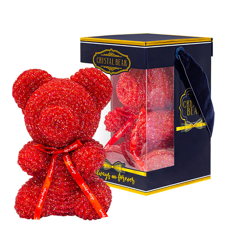 A plastic shaped red bear with glitter/crystal aesthic. Behind the bear is the packaging of the product