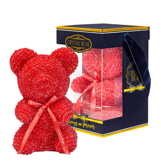 A plastic shaped red/strawberry bear with glitter/crystal aesthic. Behind the bear is the packaging of the product