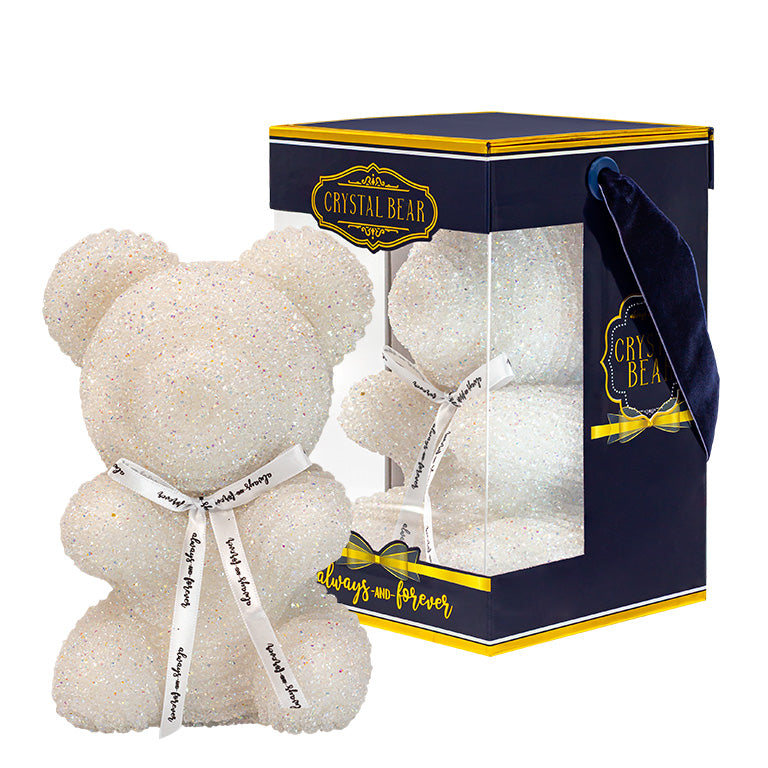 A shimmering white crystal bear with a white ribbon around its neck that reads "Always and Forever." It's displayed inside a transparent box with a navy blue and gold base, and a "CRYSTAL BEAR" label.