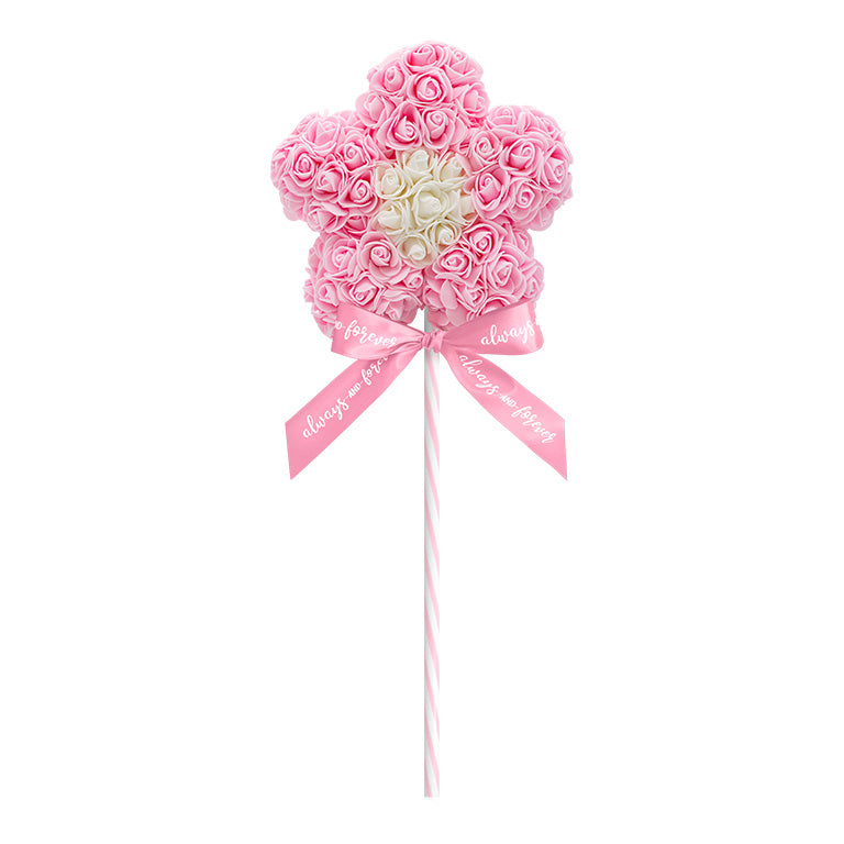 A decorative flower-shaped lollipop, crafted with a light pink floral arrangement standing on a light pink striped stick, and adorned with a light pink ribbon reading "Always and Forever." This piece is perfect for anniversaries, birthdays, graduations, Christmas, Valentine's Day, gender reveal and more. A unique and charming gift idea that can be treasured year-round.