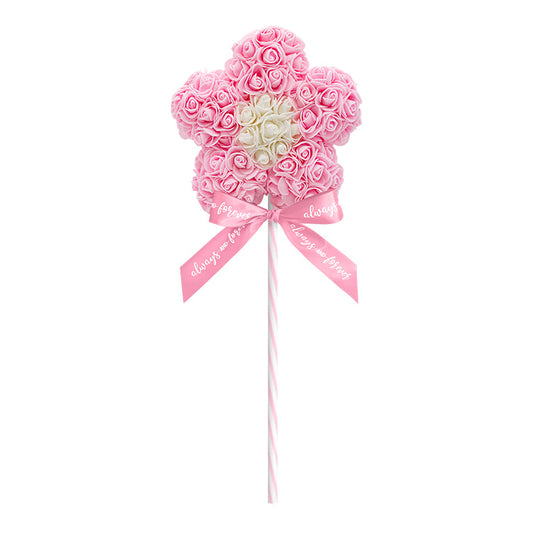A light pink artificial flower lollipop, with roses tightly arranged in a flower shape, featuring a central cluster of white roses, and a striped stick with a bow that reads "Always and Forever"