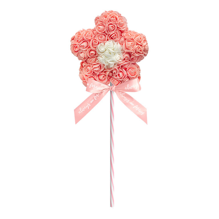 A decorative flower-shaped lollipop, crafted with a peach floral arrangement standing on a peach striped stick, and adorned with a blue ribbon reading "Always and Forever." This piece is perfect for anniversaries, birthdays, graduations, Christmas, Valentine's Day, gender reveal and more. A unique and charming gift idea that can be treasured year-round.