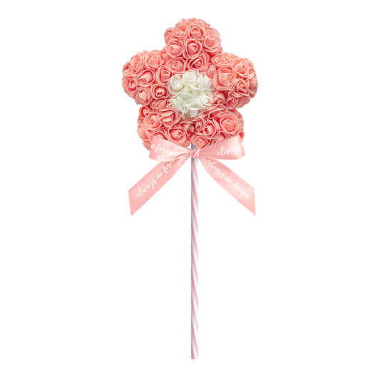 A peach artificial flower lollipop, with roses tightly arranged in a flower shape, featuring a central cluster of white roses, and a striped stick with a bow that reads "Always and Forever"