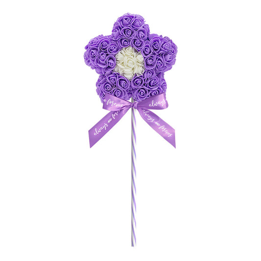 A purple artificial flower lollipop, with roses tightly arranged in a flower shape, featuring a central cluster of white roses, and a striped stick with a bow that reads "Always and Forever"