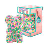 Bear made out of pink, yellow, and green-colored faux marshmallows. The bear is adorned with a green ribbon tied into a bow around its neck, and it is packaged in a clear-front gift box with a pink and white striped design. The top of the box features a teal and pink label that reads "MARSHMALLOW BEAR." This delightful creation is an excellent gift idea for various occasions such as anniversaries, birthdays, graduations, Christmas, Valentine's Day, or simply as a unique gift for someone special.	