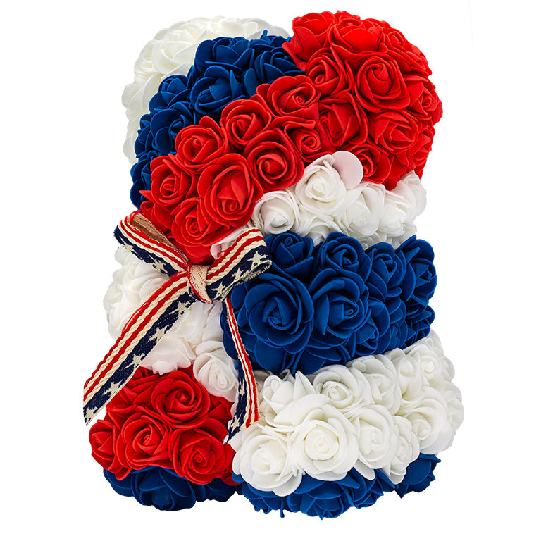 A side view of a flower bear with the colors of red, white and blue. With a bow around the neck of the American Flag design.