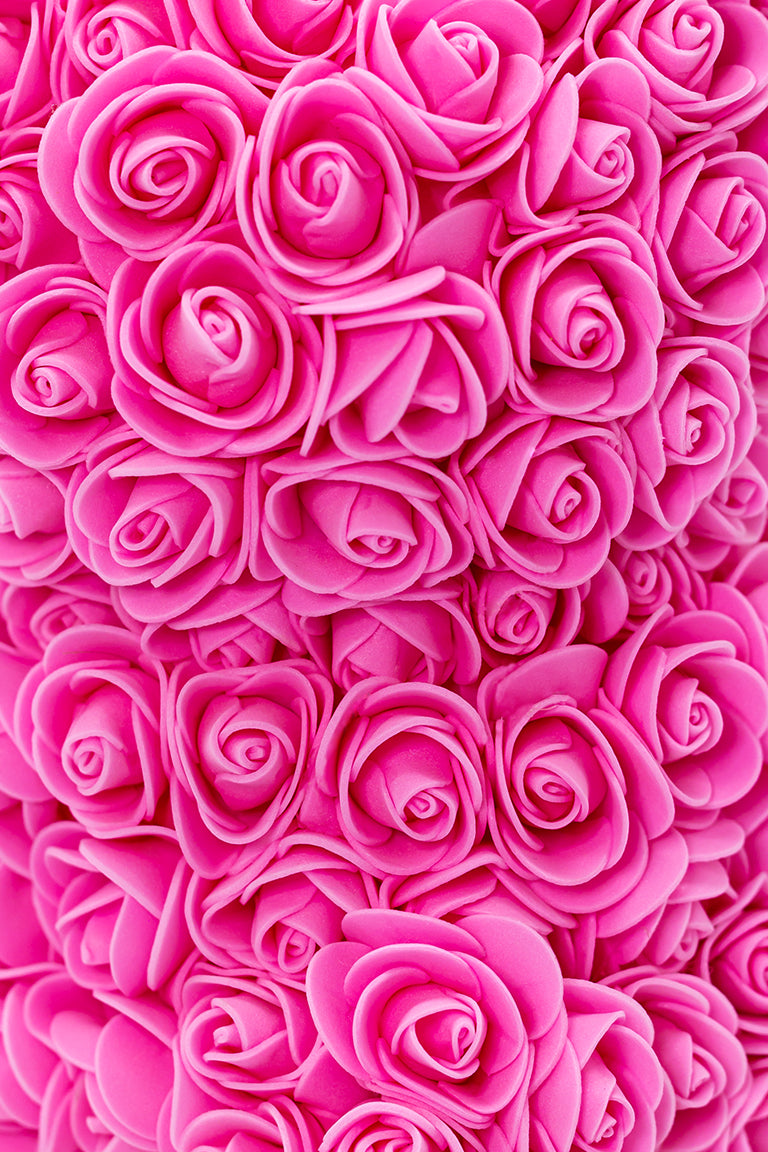 A close up view of the bear shaped product covered in foam roses in the color of pink.