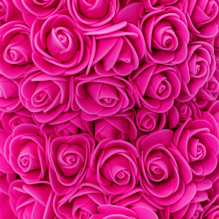 A close up view of the bear shaped product covered in foam roses in the color of rose.