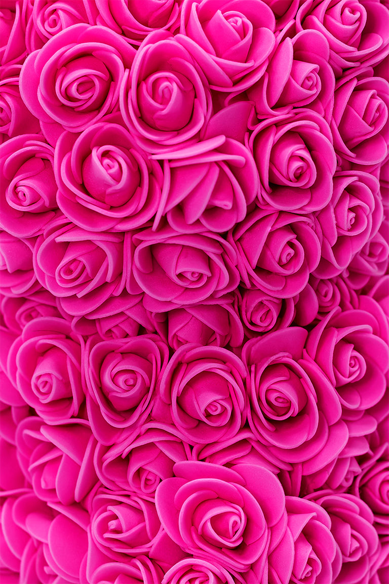 A close up view of the bear shaped product covered in foam roses in the color of rose.
