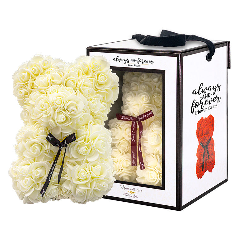 Off white cream, rose-shaped faux bloom bear with a black ribbon around its neck that includes the text "Just for You". The bear is placed next to a stylish white gift box with black accents, which has a clear window. The box comes with a black carrying handle. This intricately crafted floral bear serves as a perfect gift for various occasions such as anniversaries, birthdays, graduations, Christmas, Valentine's Day, or simply as a beautiful decorative item for those special moments.	