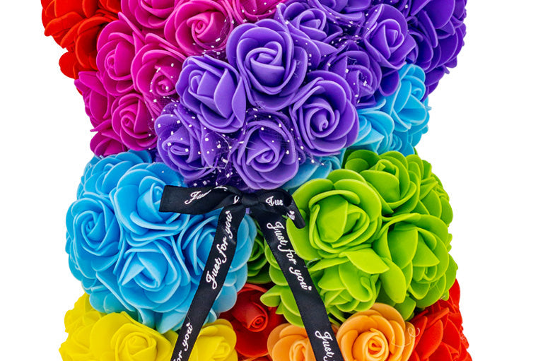 A front view of the bear shaped product covered in foam roses in the color of the rainbow.