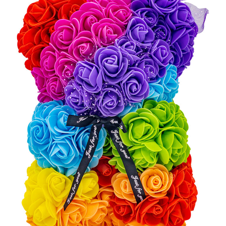 A front view of the bear shaped product covered in foam roses in the color of the rainbow.