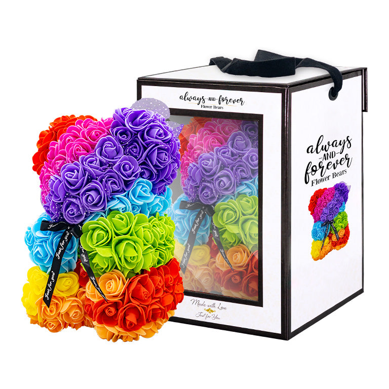 A bear shaped product covered in foam roses in the color of the rainbow. Behind the item is the packaging box of the product.