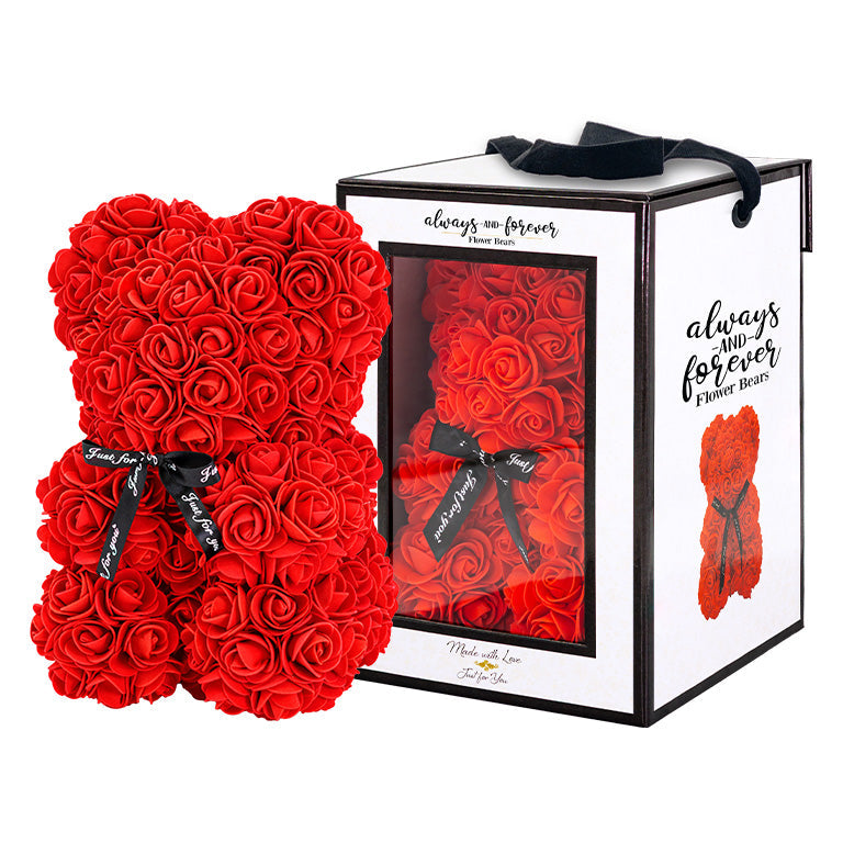 Red, rose-shaped faux bloom bear with a black ribbon around its neck that includes the text "Just for You". The bear is placed next to a stylish white gift box with black accents, which has a clear window. The box comes with a black carrying handle. This intricately crafted floral bear serves as a perfect gift for various occasions such as anniversaries, birthdays, graduations, Christmas, Valentine's Day, or simply as a beautiful decorative item for those special moments.	